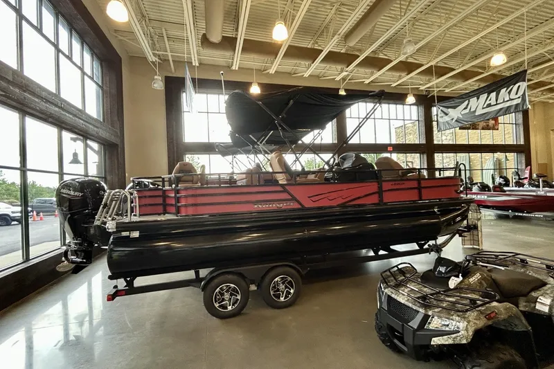 The Image of 2026 Ranger 220F pontoon boat displayed indoors with trailer and outboard motor. - 0