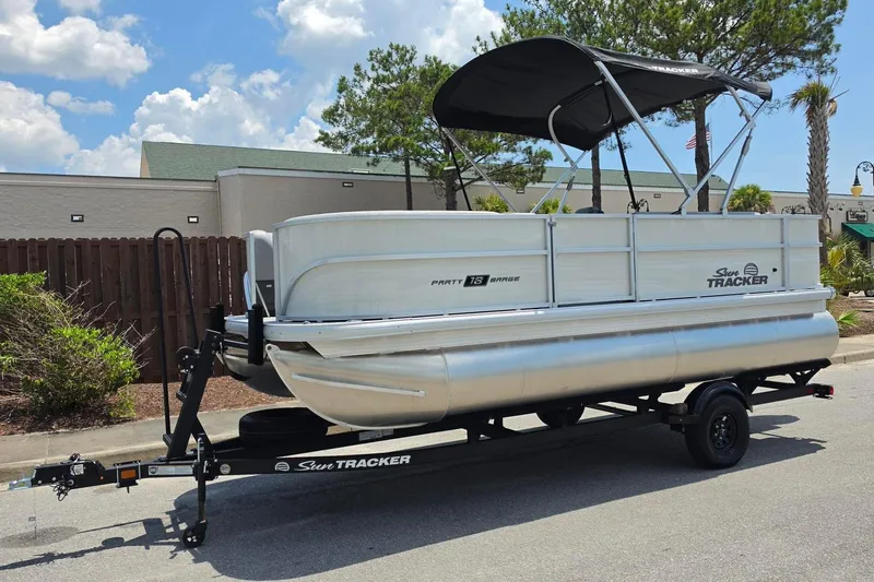 Slide: The Image of 2026 Sun Tracker Party Barge 18 DLX pontoon boat on trailer, parked outdoors. - 7