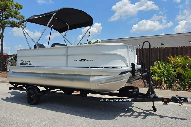 Slide: The Image of 2026 Sun Tracker Party Barge 18 DLX pontoon boat on trailer, parked outdoors. - 4
