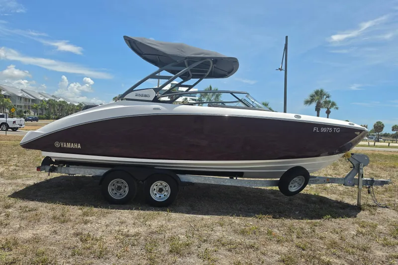 Slide: The Image of 2022 Yamaha Boats 252SD on trailer, parked outdoors under clear sky. - 1