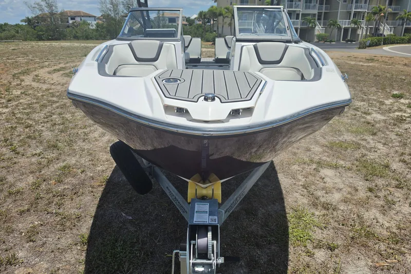 Slide: The Image of 2022 Yamaha Boats 252SD on trailer, parked on grassy area near residential buildings. - 11