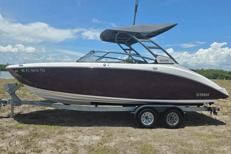 Slide: The Image of 2022 Yamaha Boats 252SD on trailer, sleek design, black hull, sunny day background. - 8