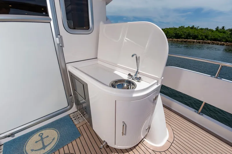 Slide: The Image of An outdoor kitchenette with a sink on a boat, surrounded by water and greenery. - 13