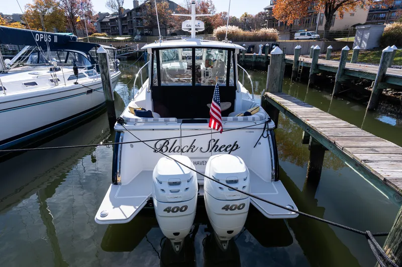Slide: The Image of 2023 Back Cove 340 boat docked, displaying twin 400 engines and American flag. - 68