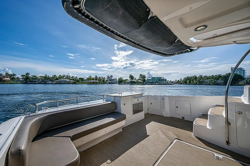 Slide: The Image of 2010 Sea Ray 520 Sedan Bridge yacht deck with waterfront view and clear blue sky. - 16