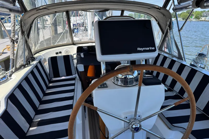 Slide: The Image of Interior view of a 2007 Hylas H49 sailboat cockpit with striped seating and Raymarine navigation. - 1