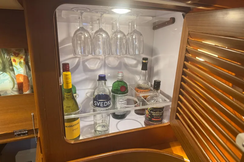 Slide: The Image of Bar cabinet on 2007 Hylas H49 yacht with assorted liquor bottles and hanging glasses. - 19