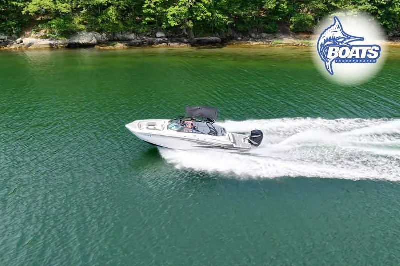 Slide: The Image of 2020 Monterey M-65 boat cruising on a serene lake with lush green shoreline. - 2