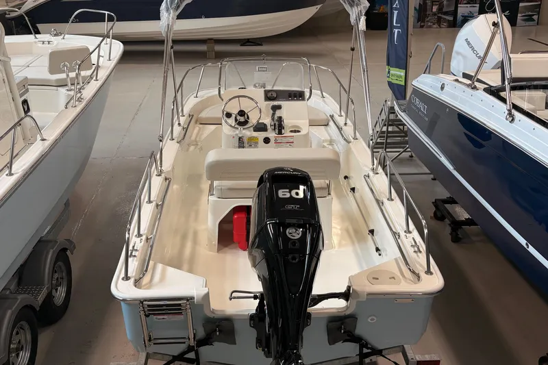 Slide: The Image of 2026 Boston Whaler 150 Montauk boat displayed in showroom, featuring Mercury outboard engine. - 1