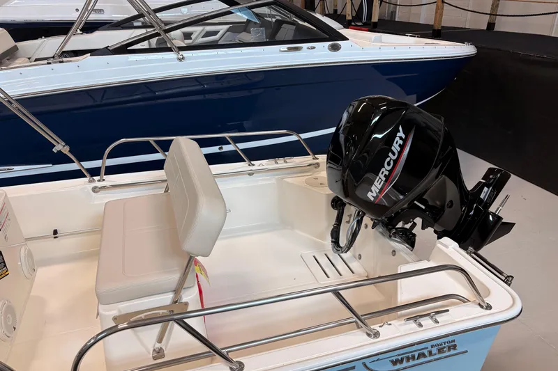 Slide: The Image of 2026 Boston Whaler 150 Montauk boat with Mercury engine, white seating, and sleek design. - 4