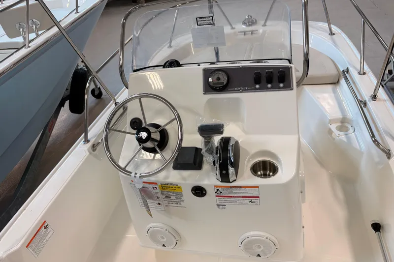 Slide: The Image of 2026 Boston Whaler 150 Montauk boat console with steering wheel and controls. - 7