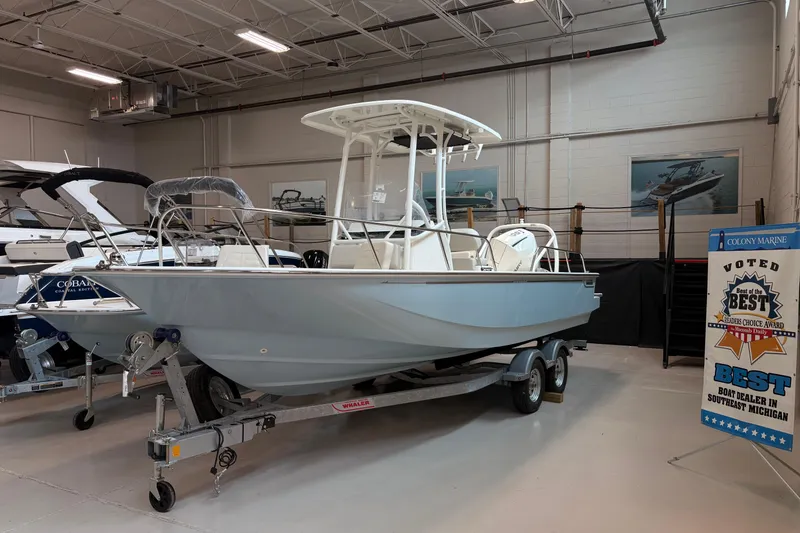 The Image of 2026 Boston Whaler 210 Montauk boat displayed indoors on a trailer. - 1