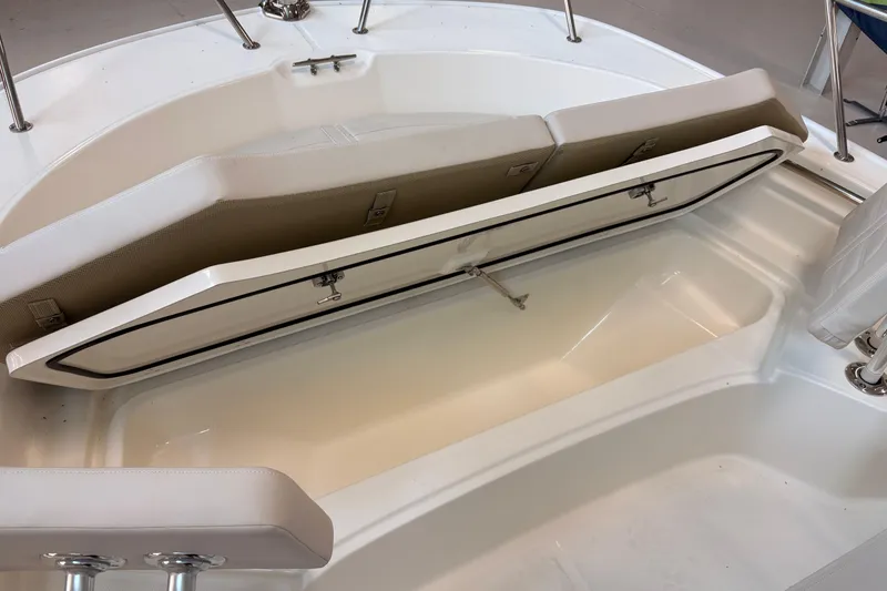 Slide: The Image of 2026 Boston Whaler 210 Montauk boat storage compartment with open lid and cushioned seating. - 12