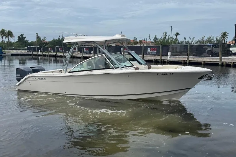 Slide: The Image of 2020 Cobia 280 Dual Console boat docked in marina, calm water, overcast sky. - 2