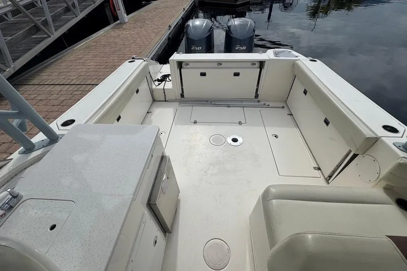 Slide: The Image of 2020 Cobia 280 Dual Console boat interior with spacious seating and twin engines at dock. - 21