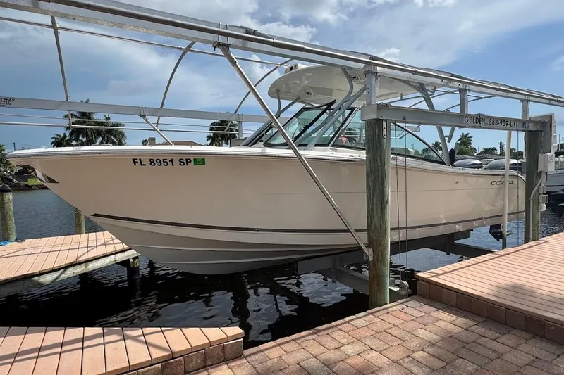 Slide: The Image of 2020 Cobia 280 Dual Console boat on lift at dockside, sunny day. - 45