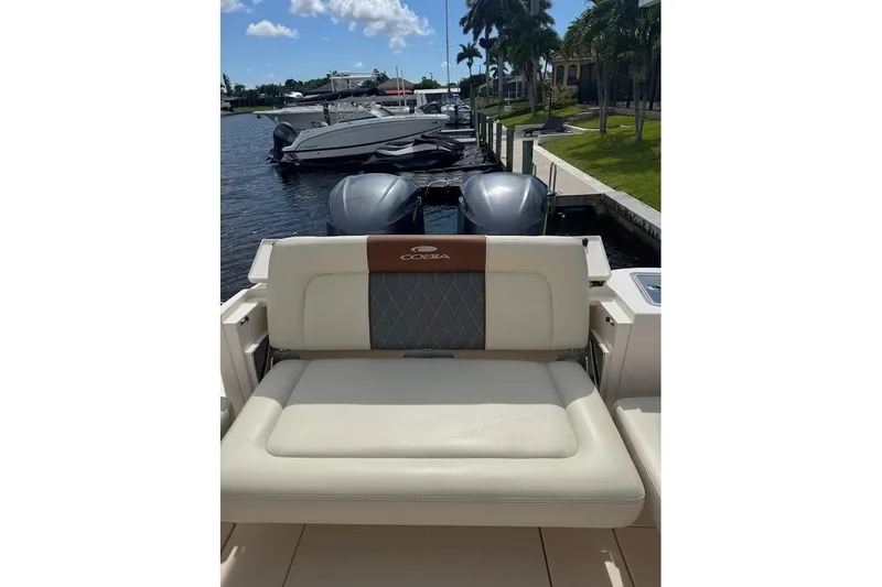 Slide: The Image of 2020 Cobia 280 Dual Console boat with cushioned seating, docked by a waterfront. - 23