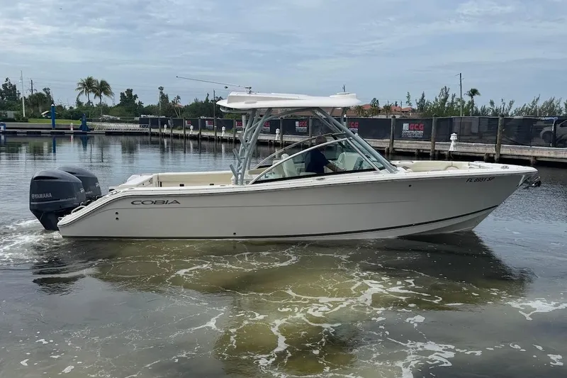 Slide: The Image of 2020 Cobia 280 Dual Console boat on calm water near a marina. - 4