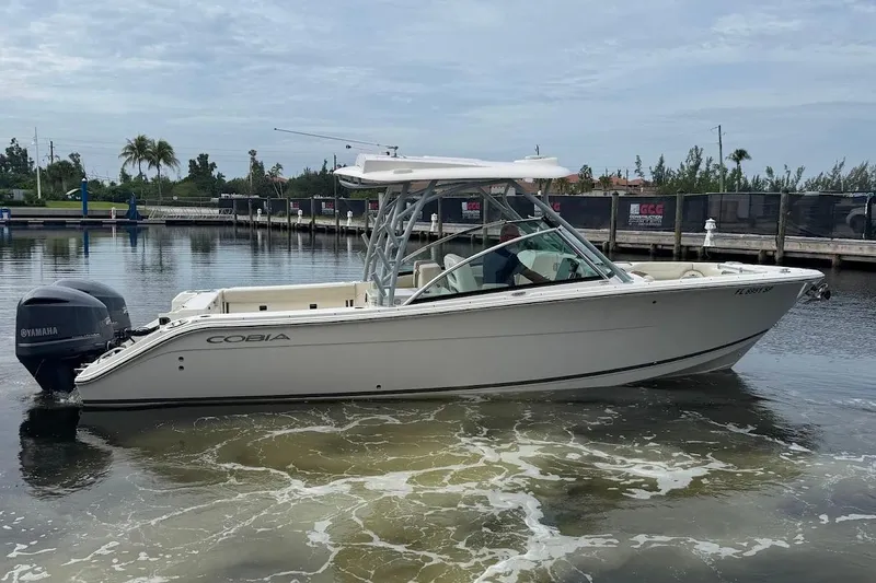 Slide: The Image of 2020 Cobia 280 Dual Console boat on calm water, featuring Yamaha outboard engines. - 5