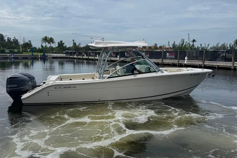 Slide: The Image of 2020 Cobia 280 Dual Console boat docked in a marina, featuring Yamaha outboard engines. - 6