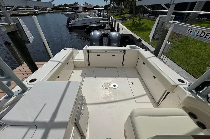 Slide: The Image of 2020 Cobia 280 Dual Console boat interior with spacious seating and twin engines at dock. - 34