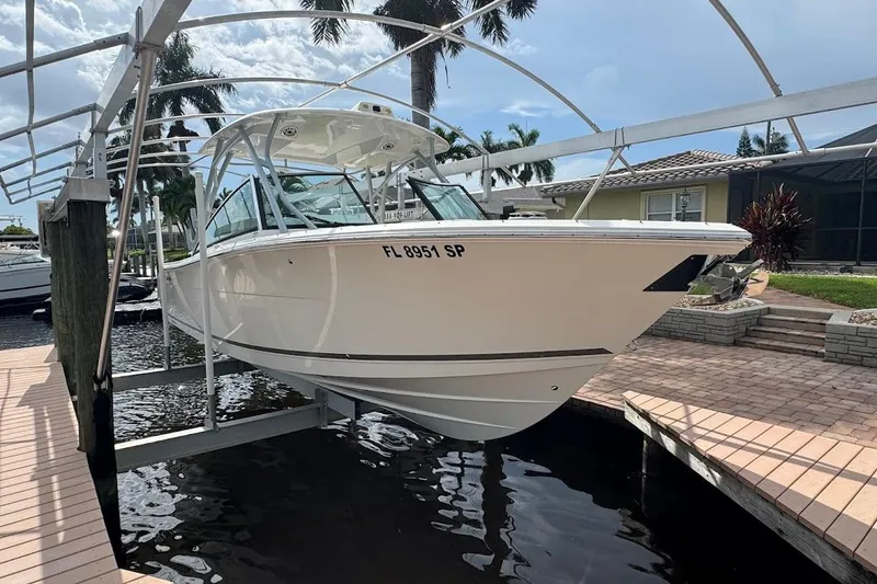 Slide: The Image of 2020 Cobia 280 Dual Console boat on lift, docked near waterfront home. - 47