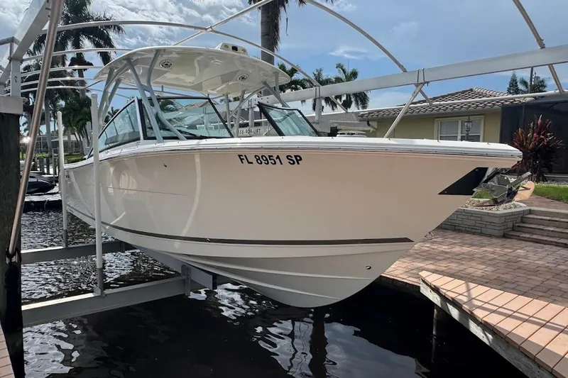 Slide: The Image of 2020 Cobia 280 Dual Console boat on lift, docked near waterfront home. - 46