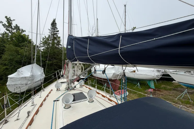 Slide: The Image of 1989 Sabre 34 MK II sailboat on land, surrounded by covered boats and trees. - 26