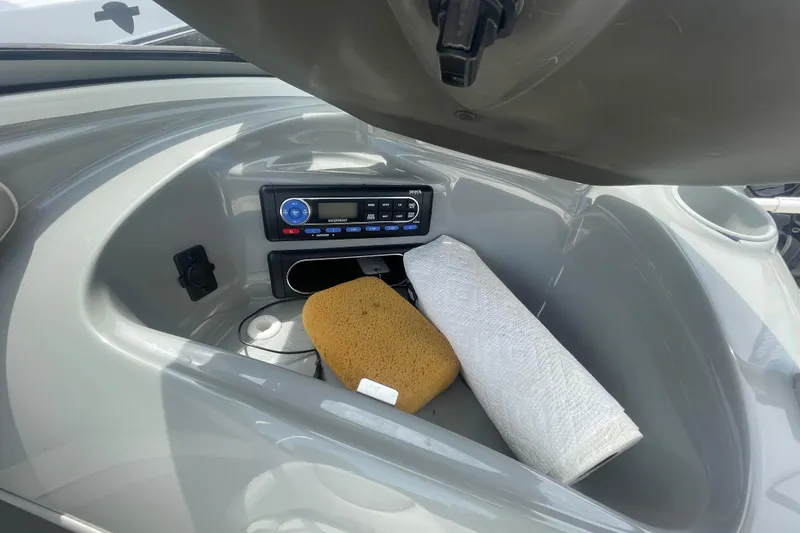 Slide: The Image of Storage compartment in a 2008 Bayliner 195 Bowrider with radio, sponge, and paper towels. - 10
