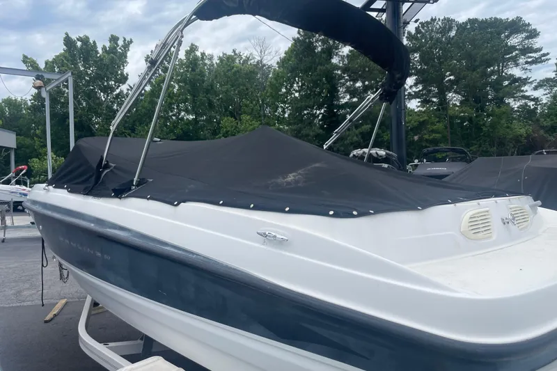 Slide: The Image of 2008 Bayliner 195 Bowrider with cover, parked outdoors, surrounded by trees. - 17