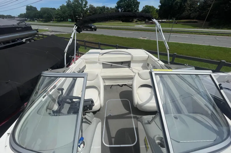Slide: The Image of 2008 Bayliner 195 Bowrider boat with open seating and windshield, parked near a road. - 5