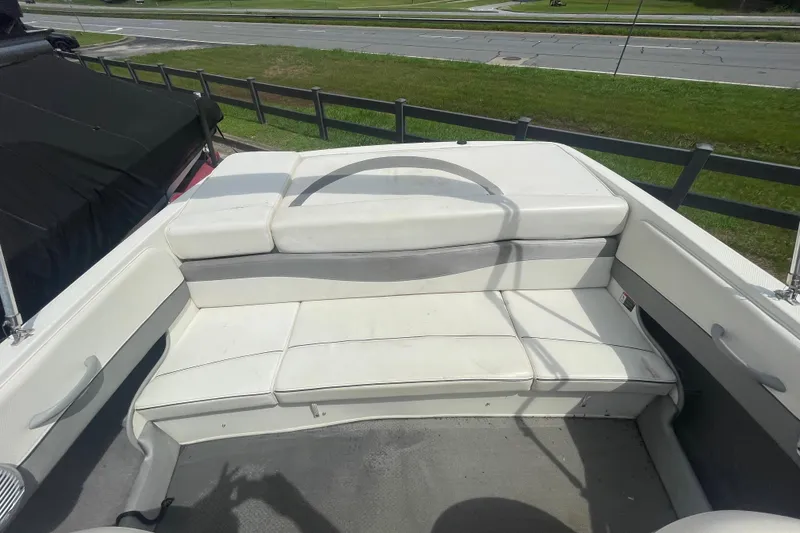 Slide: The Image of 2008 Bayliner 195 Bowrider interior with white seating, parked near a road. - 9