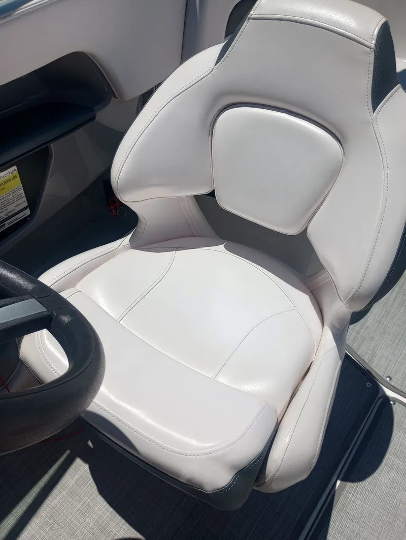 Slide: The Image of A white leather seat on a boat with a steering wheel beside it. - 33
