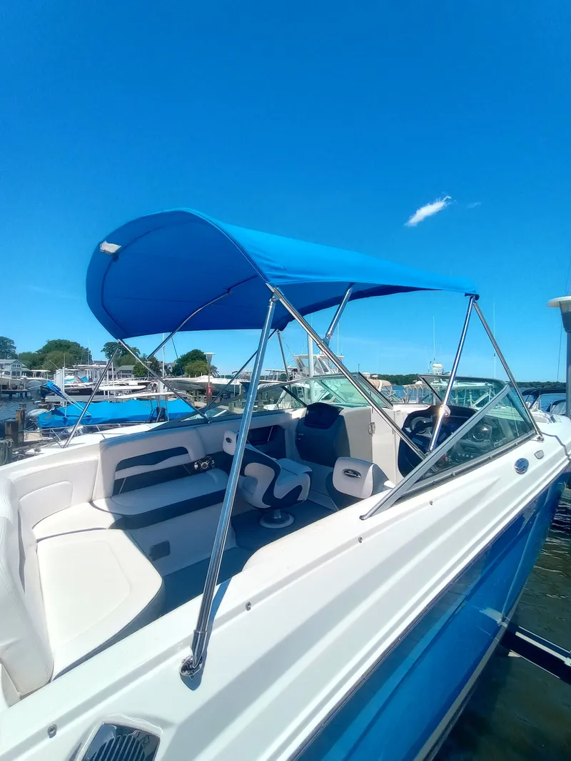 Slide: The Image of A Chaparral 240SSI boat with a blue canopy, docked on water, under a clear sky. - 7