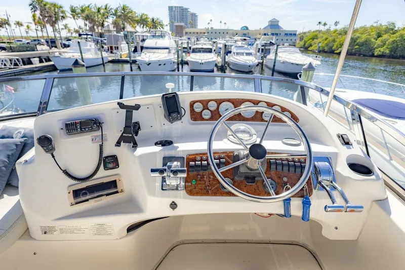 Slide: The Image of 2001 Silverton 410 Sport Bridge helm with marina view, featuring steering wheel and controls. - 40