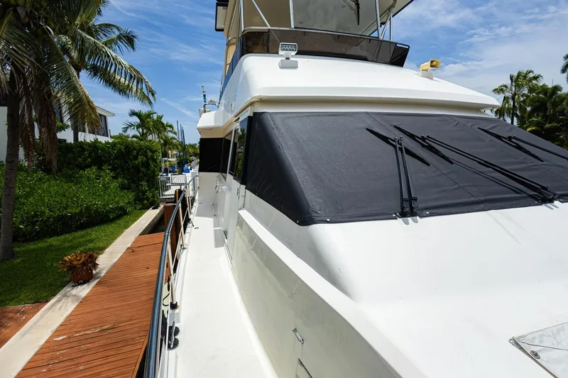 Slide: The Image of 1990 Viking Cockpit Motor Yacht docked, surrounded by lush greenery and palm trees. - 60
