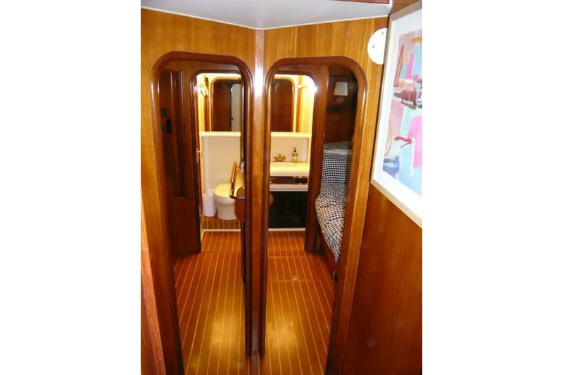 Slide: The Image of 1990 Viking Cockpit Motor Yacht interior with wood paneling, bathroom, and cozy sleeping area. - 43