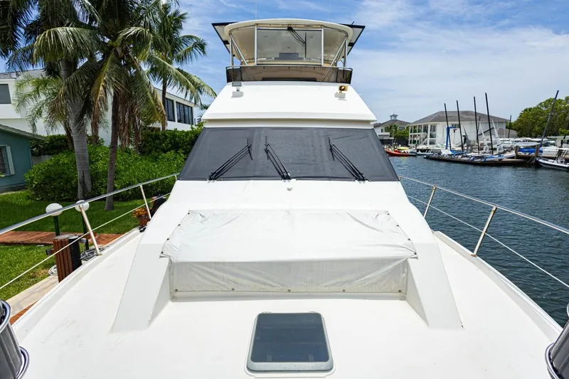Slide: The Image of 1990 Viking Cockpit Motor Yacht docked by palm trees and waterfront homes. - 59