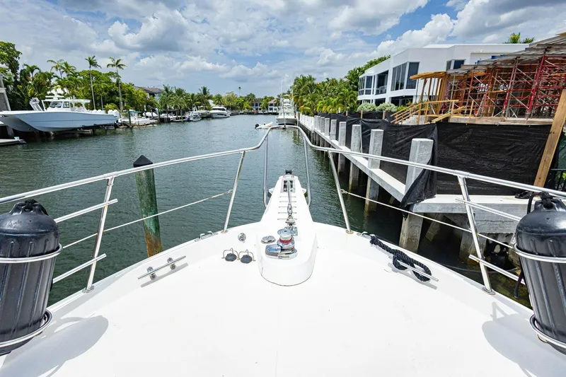 Slide: The Image of 1990 Viking Cockpit Motor Yacht cruising through a scenic canal with palm trees and modern homes. - 58