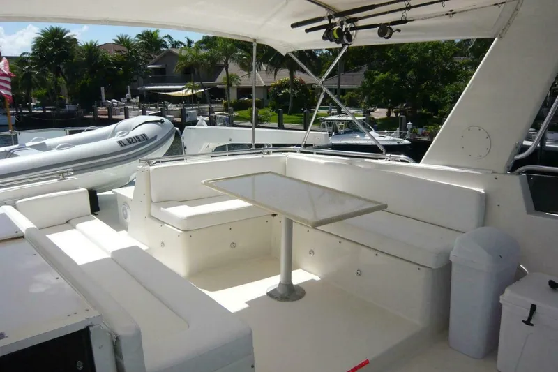 Slide: The Image of Spacious cockpit of 1990 Viking Motor Yacht with seating and table, docked near lush greenery. - 63