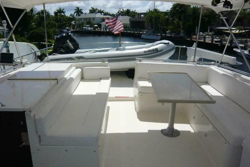 Slide: The Image of 1990 Viking Cockpit Motor Yacht with seating area and table, docked near palm trees. - 62