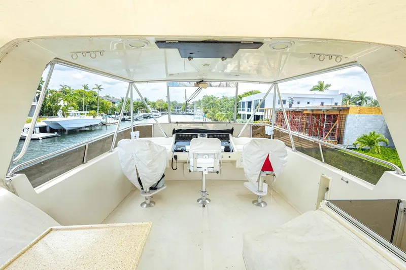 Slide: The Image of 1990 Viking Cockpit Motor Yacht interior with helm, covered seats, and waterfront view. - 53