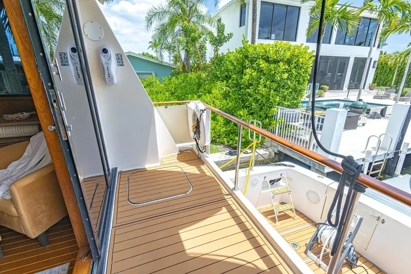 Slide: The Image of 1990 Viking Cockpit Motor Yacht deck with teak flooring, docked near a modern waterfront home. - 17