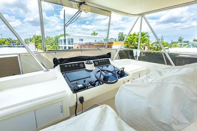 Slide: The Image of Cockpit view of a 1990 Viking Motor Yacht, featuring steering controls and a scenic waterfront backdrop. - 52