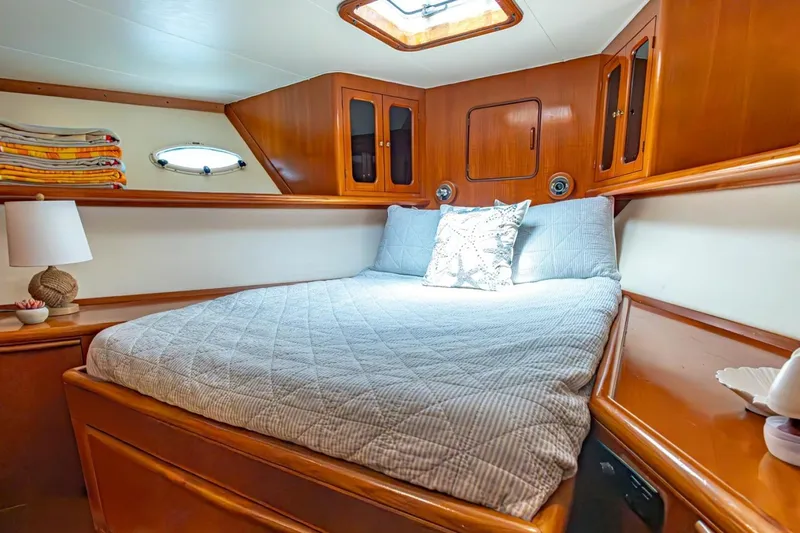 Slide: The Image of Cozy cabin interior of 1990 Viking Cockpit Motor Yacht with wooden accents and comfortable bedding. - 33