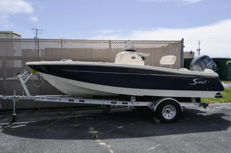 Slide: The Image of 2026 Scout 188 Sportfish boat on trailer, parked outdoors, side view. - 0