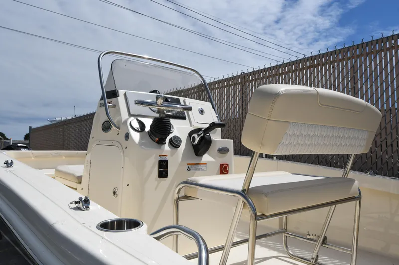 Slide: The Image of 2026 Scout 188 Sportfish boat interior with steering console and seating, under a partly cloudy sky. - 8