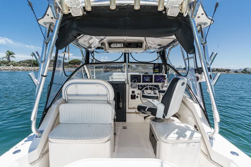 Slide: The Image of 1999 Albemarle 290 Express Fisherman boat interior with helm and seating, on calm water. - 29