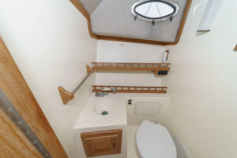 Slide: The Image of 1999 Albemarle 290 Express Fisherman boat bathroom with sink, toilet, and wooden shelving. - 57
