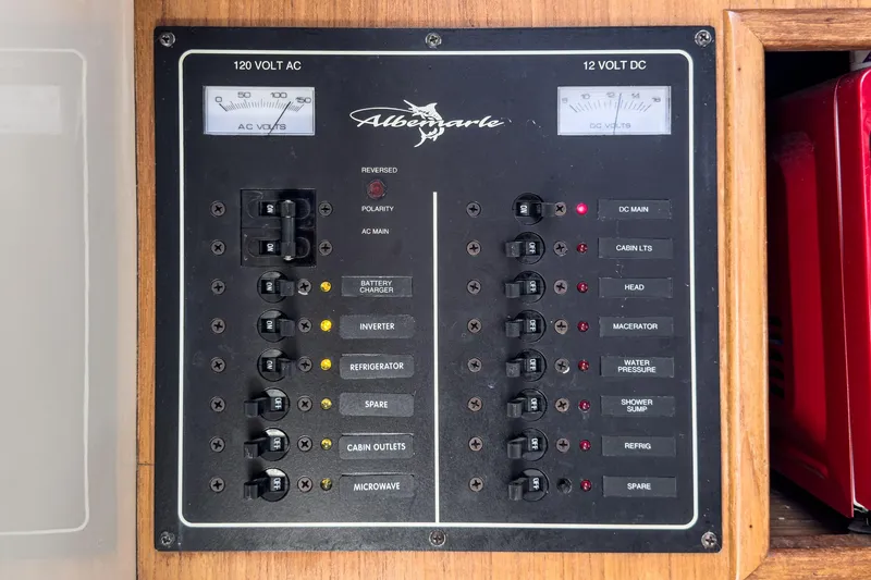 Slide: The Image of Electrical control panel of a 1999 Albemarle 290 Express Fisherman boat, featuring AC and DC switches. - 58